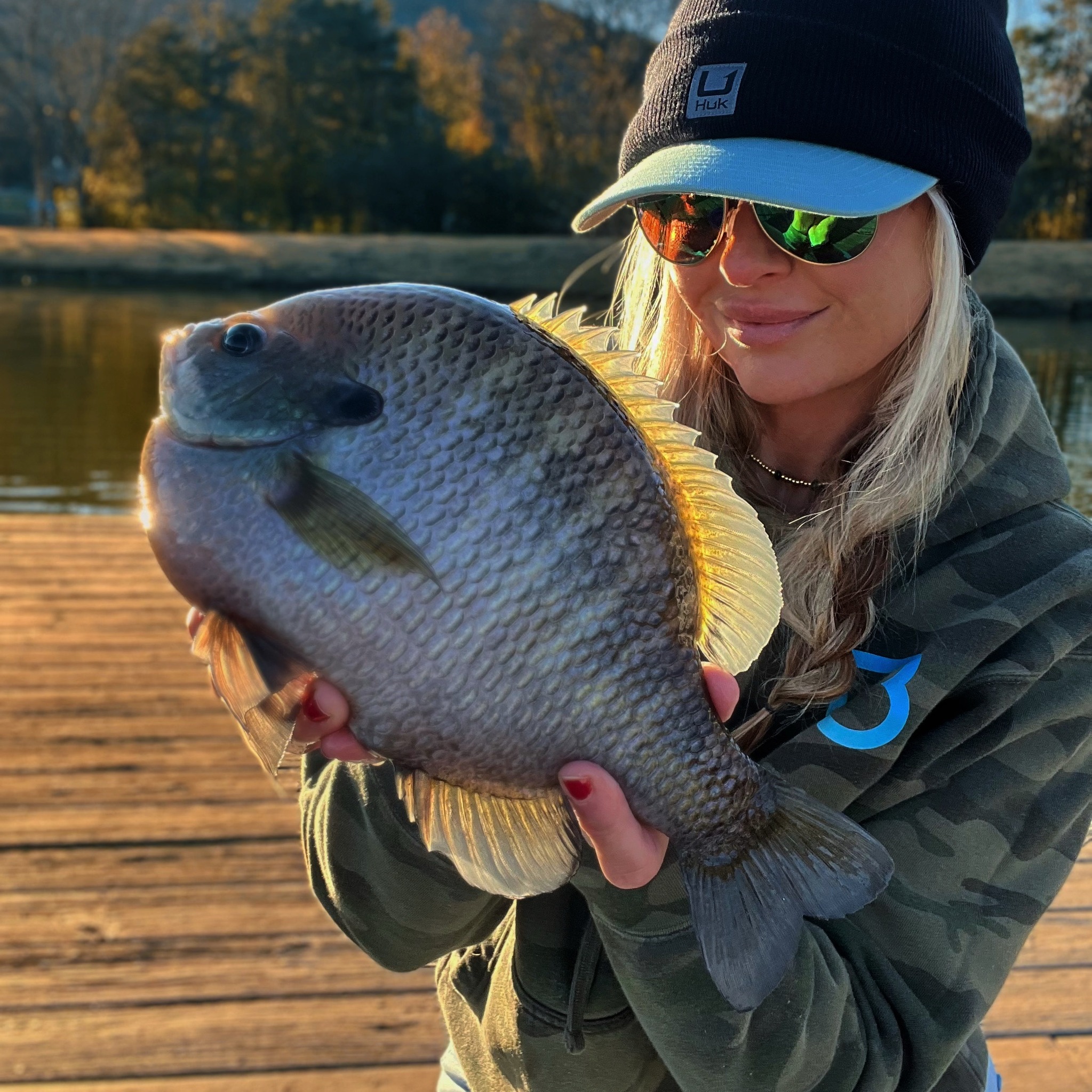 Sarah Parvin holding a massive coppernose bluegill at golden hour on the Slab Lab dock